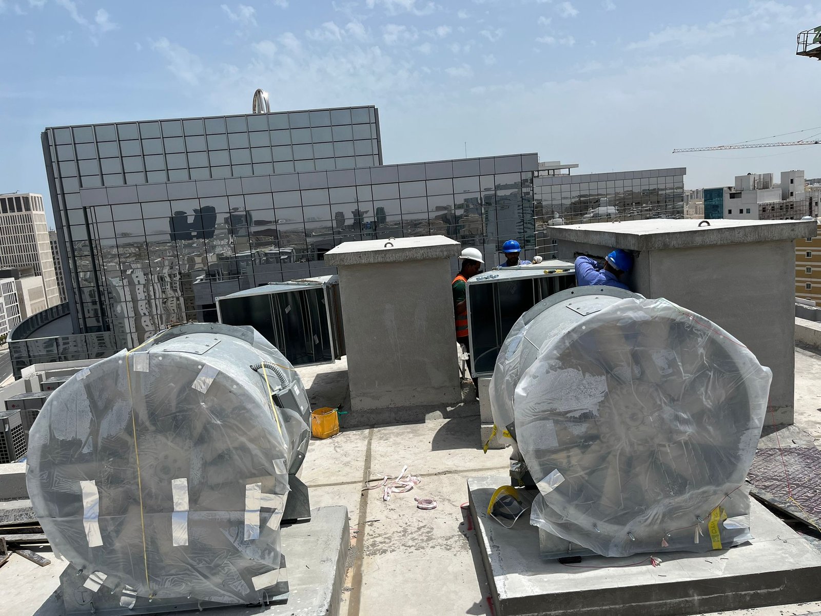 Rooftop HVAC ventilation system installation with industrial exhaust fans and ductwork on a commercial building.